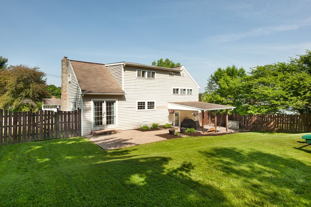Side view of a white suburban house with attached garage and well-maintained lawn.