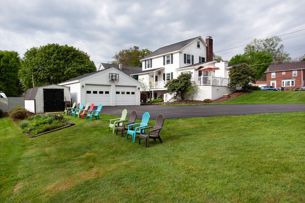 Wide view of a residential property showing white houses and garages nestled in a green hillside setting.