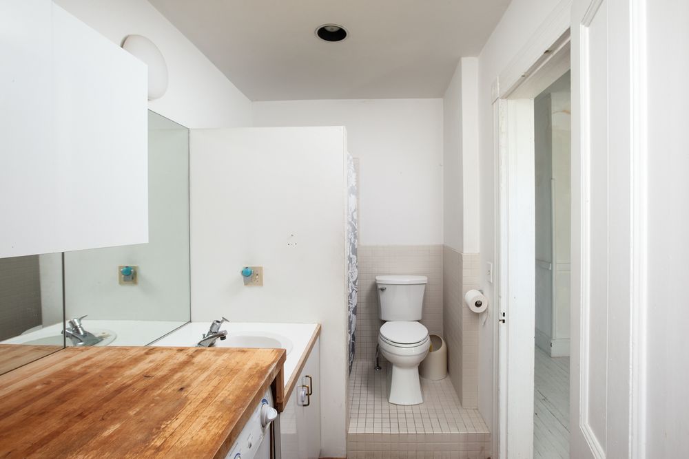 Modern white bathroom interior with wooden countertop and minimalist fixtures.