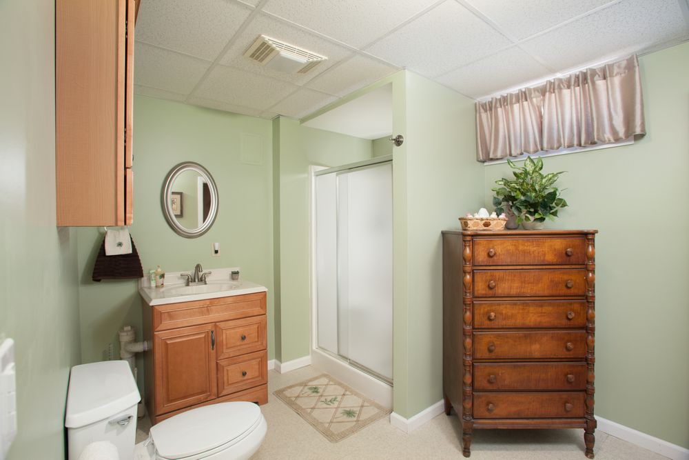 Mint green bedroom with wooden dressers and soft natural lighting.