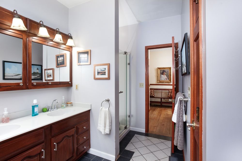 Modern bathroom with white vanity, wooden trim, and bright lighting fixtures mounted above mirror.