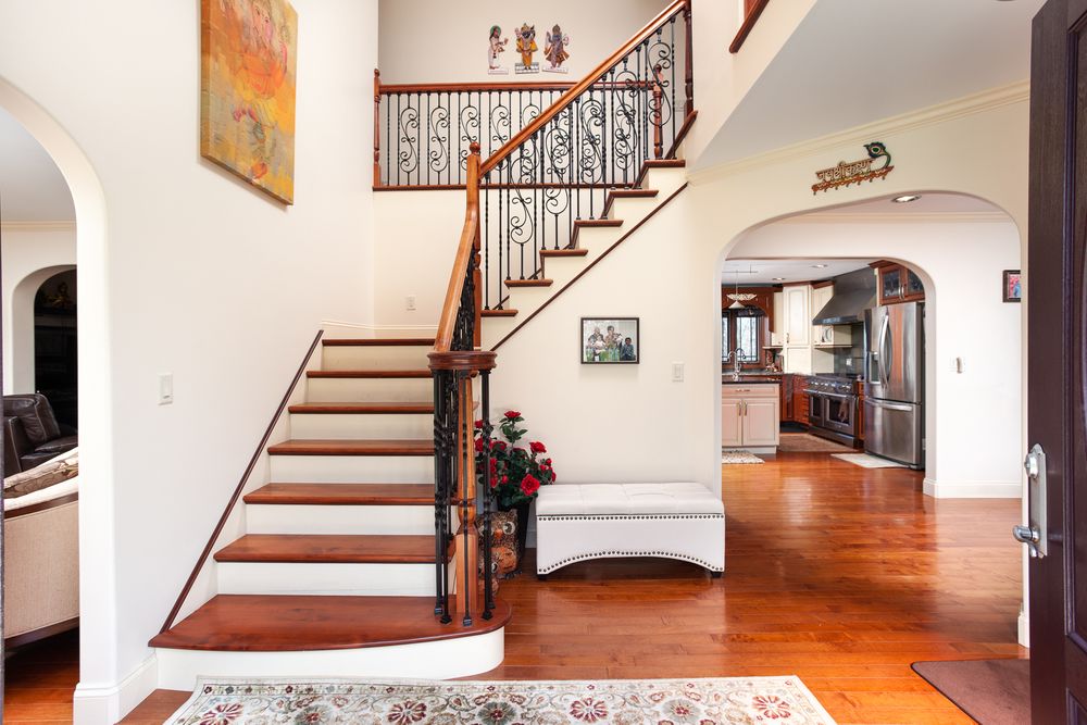 Traditional staircase with wooden steps, white walls, and decorative iron railings.