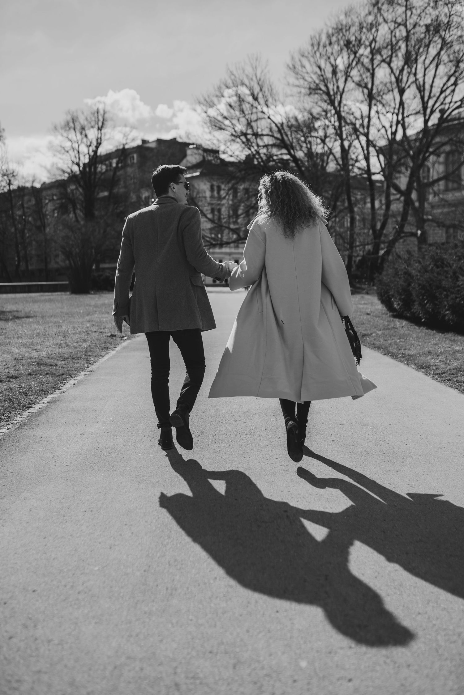 Black and white series of shadows cast by a couple walking on a path through a park.