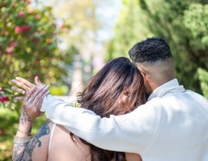 Couple embracing in a garden with colorful flowers and greenery.