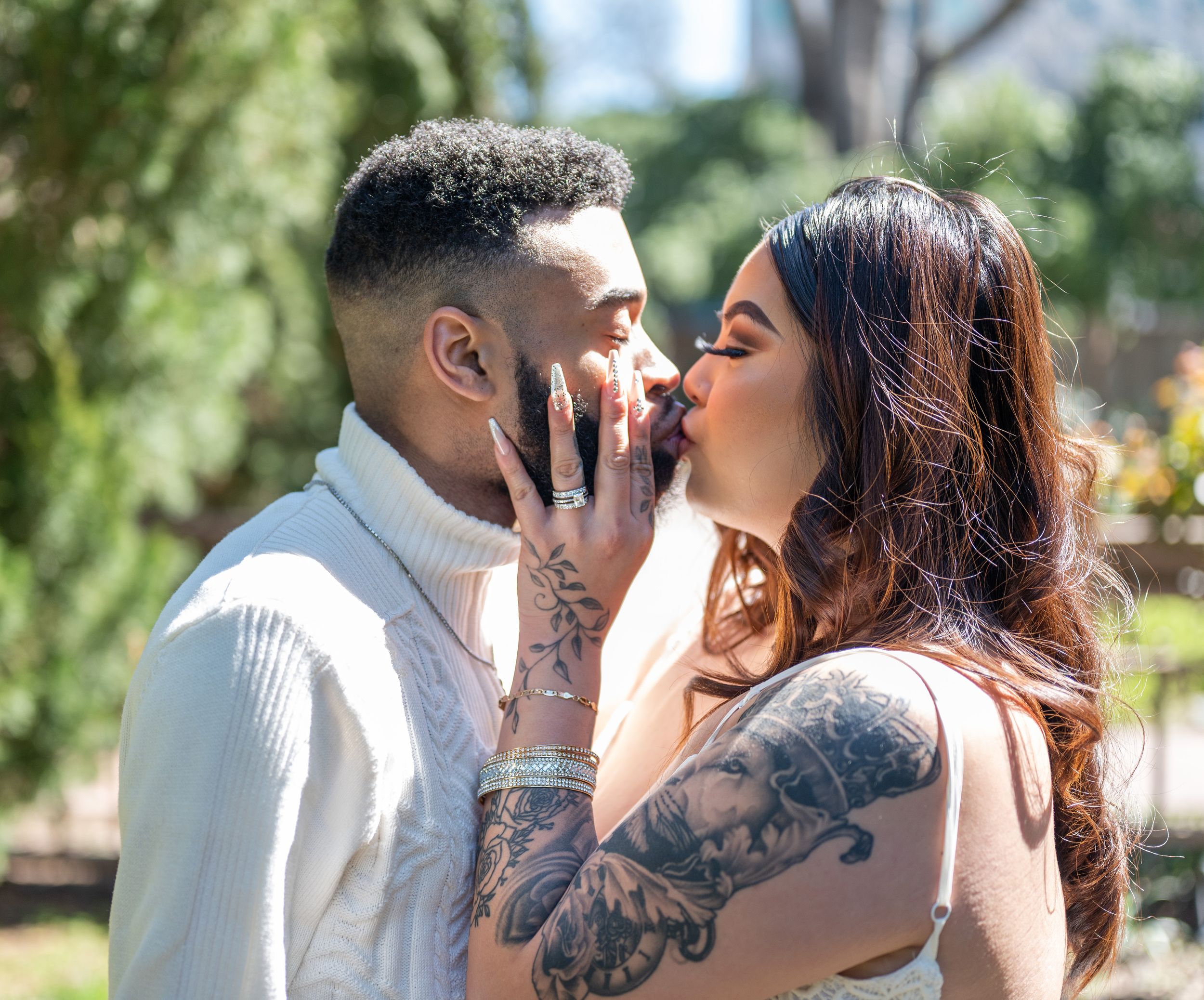 A romantic couple sharing an intimate kiss in a garden setting.