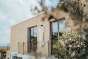 A white wedding dress hangs outside against a modern building facade.