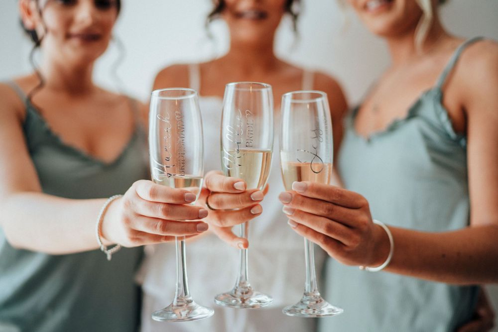 Three hands holding champagne glasses together in celebration.