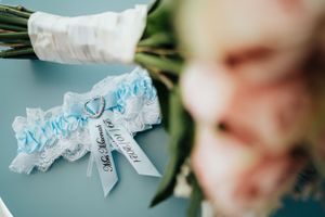 Blue and white wedding garter with bow detail on bouquet stem.