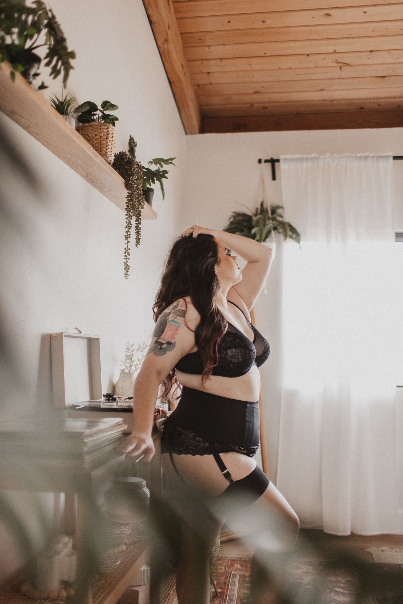 Intimate boudoir photo with indoor plants and natural window light.