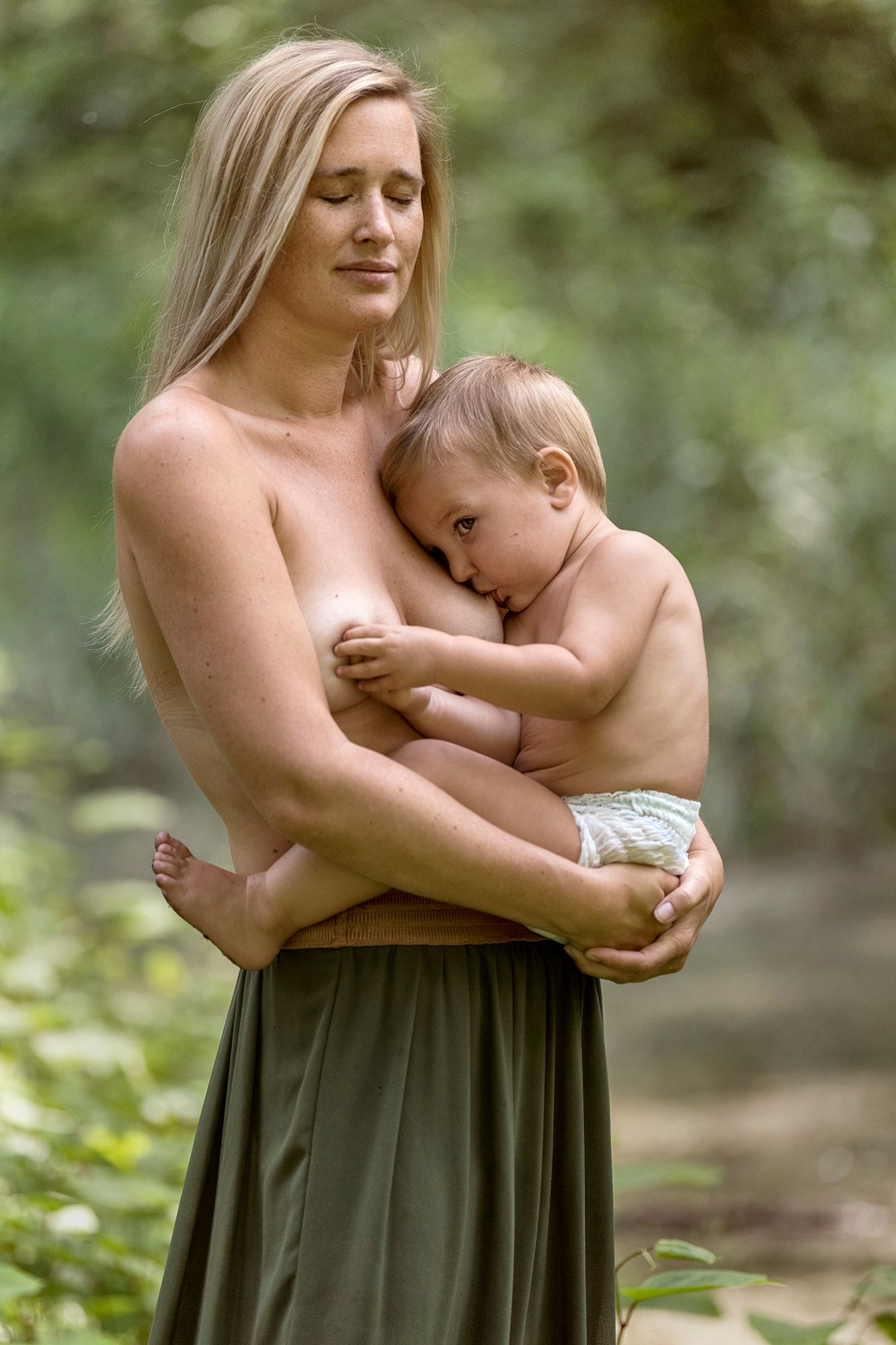 borstvoedingsfoto van een halfnaakte mama met baby in de natuur