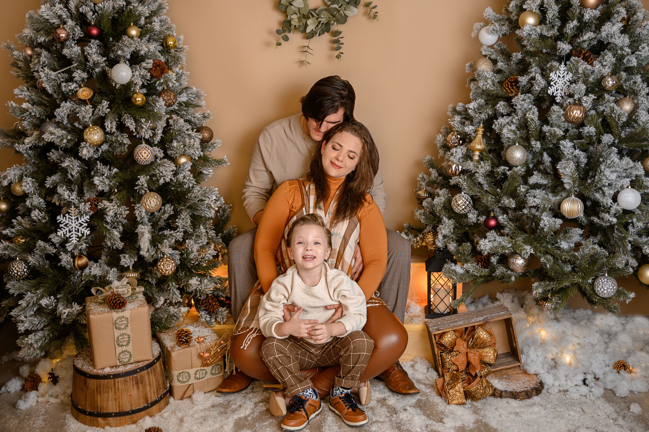 Festive Christmas photo setup with decorated trees, wooden props, and warm lighting.