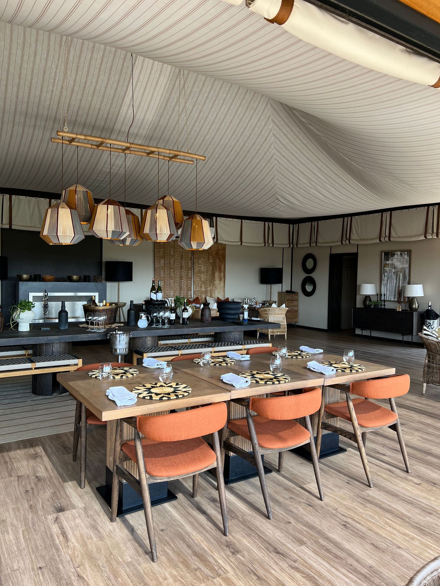 Contemporary dining area with orange chairs and pendant lighting featuring wooden flooring.