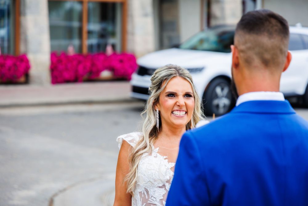 A romantic wedding moment captured outdoors with bright pink flowers in the background.