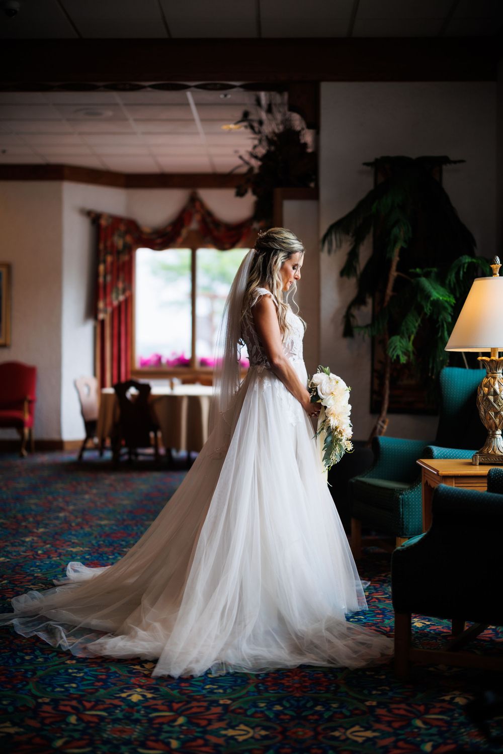 A flowing white wedding gown with a long train photographed in an elegant hotel interior.