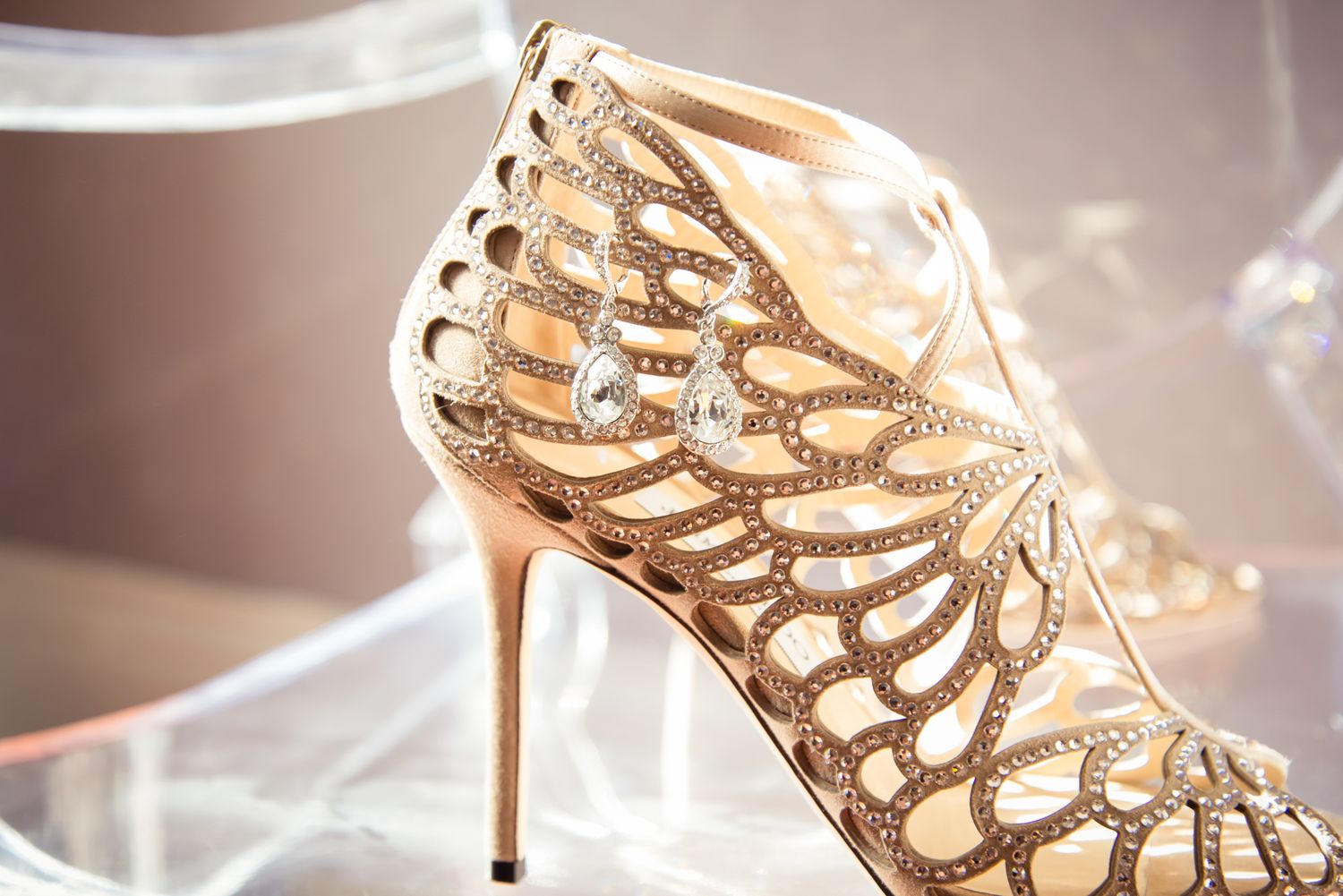 An elegant nude-colored designer high heel with intricate cutout pattern details.