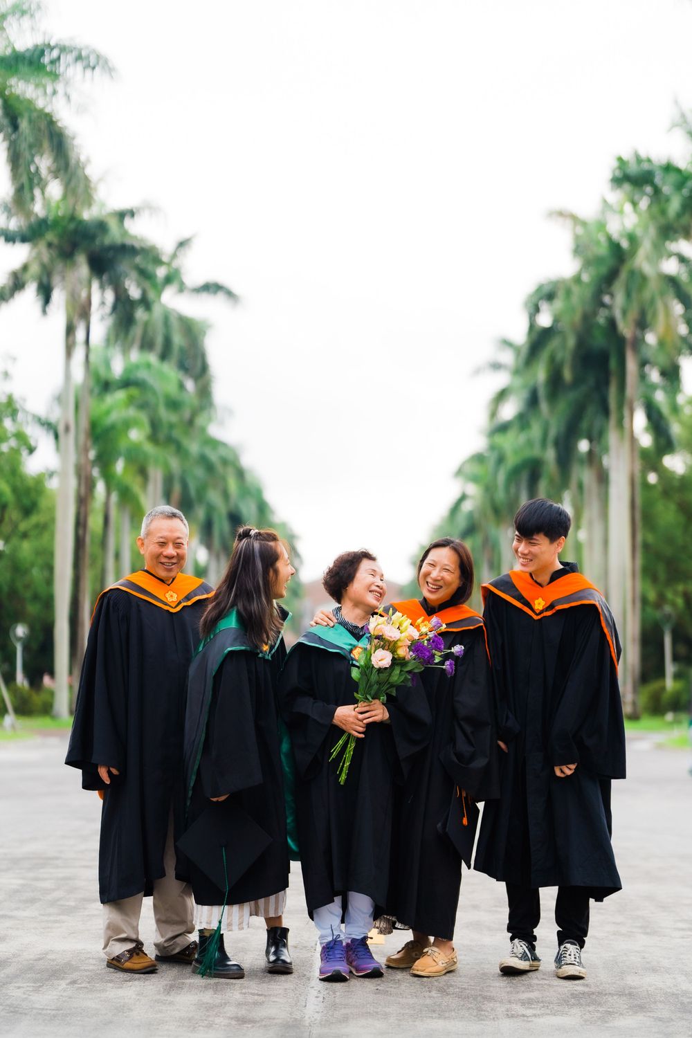 Candid group shot of graduation celebration with professors and graduate holding flowers.