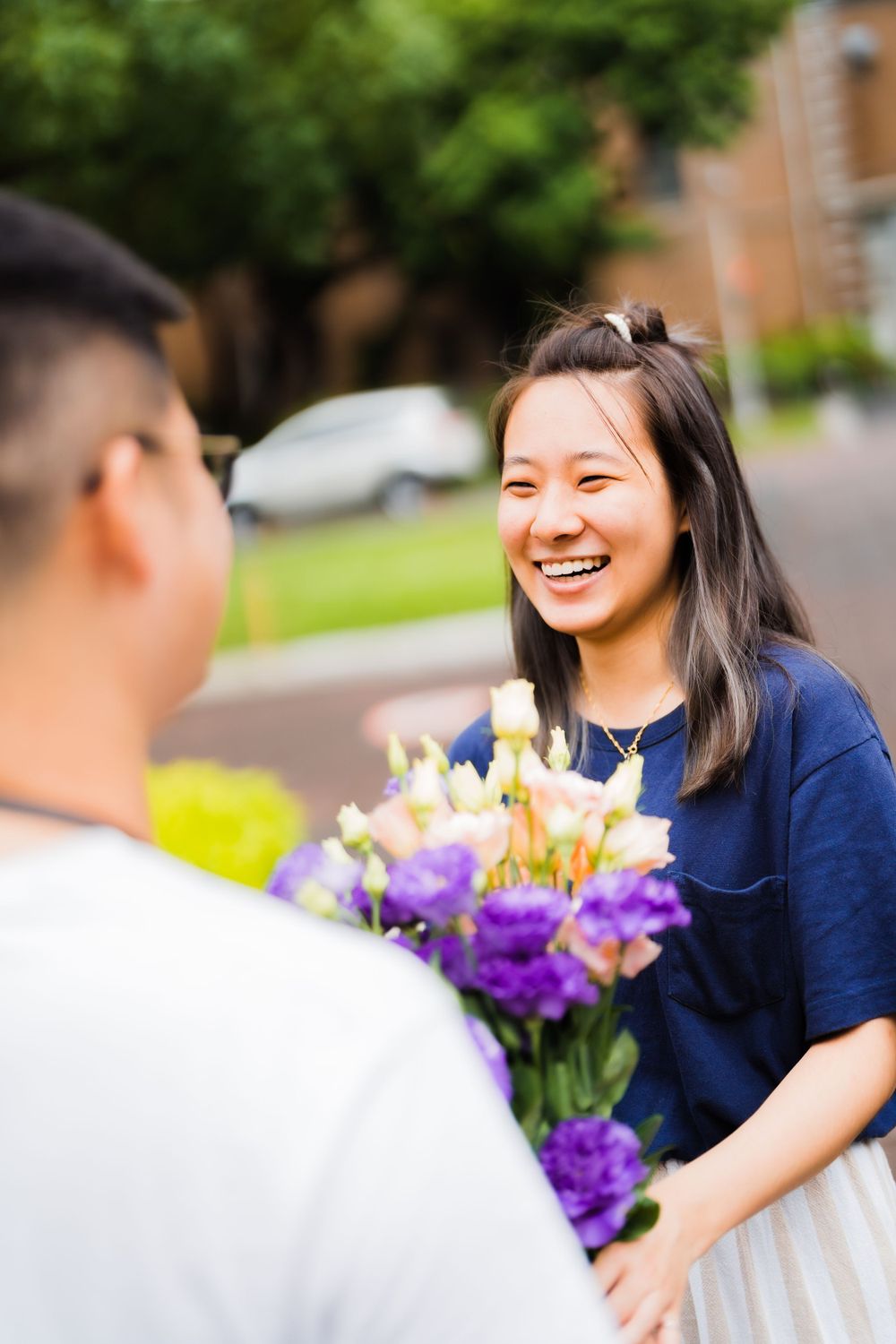 Person receiving a colorful bouquet of flowers with purple and yellow blooms.