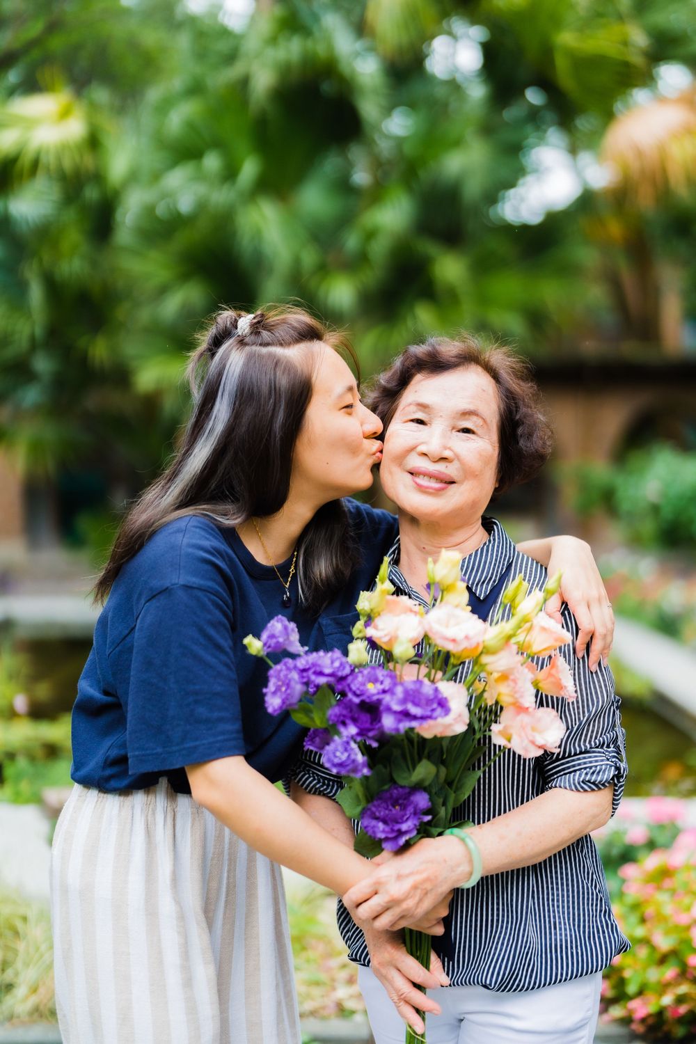 A heartwarming moment shared between family members with a colorful bouquet in a garden setting.