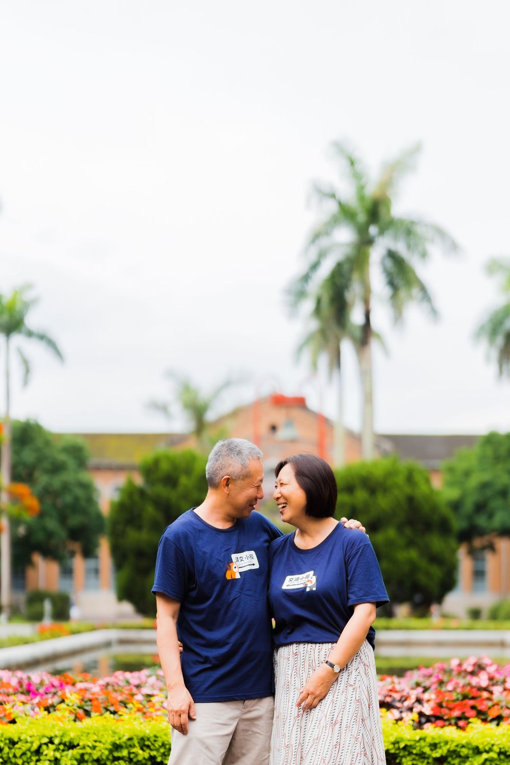 Couple in matching navy shirts sharing a tender moment in a tropical garden.