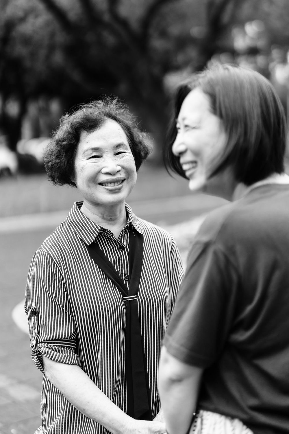 Black and white portrait of two people sharing a heartfelt laugh outdoors.