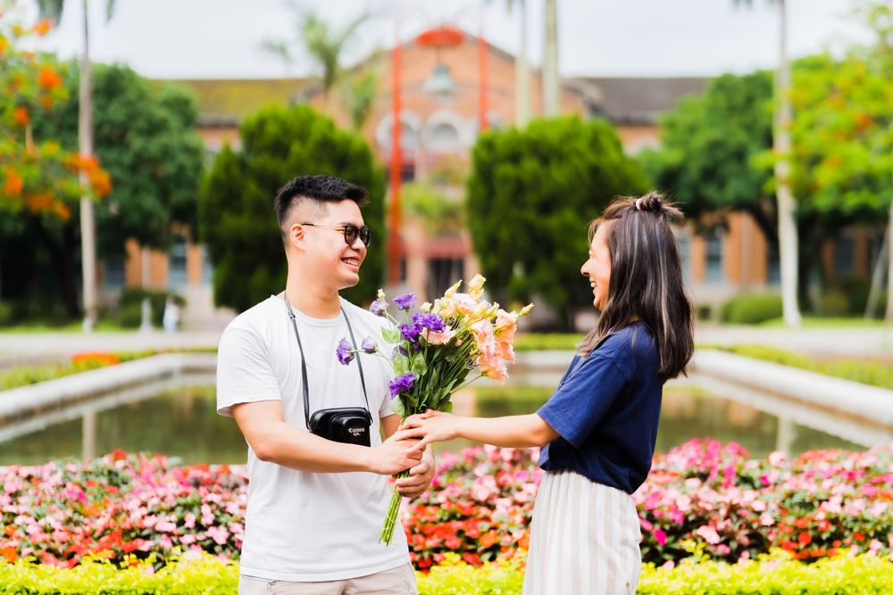 Romantic moment exchanging flowers in a tropical garden with palm trees.