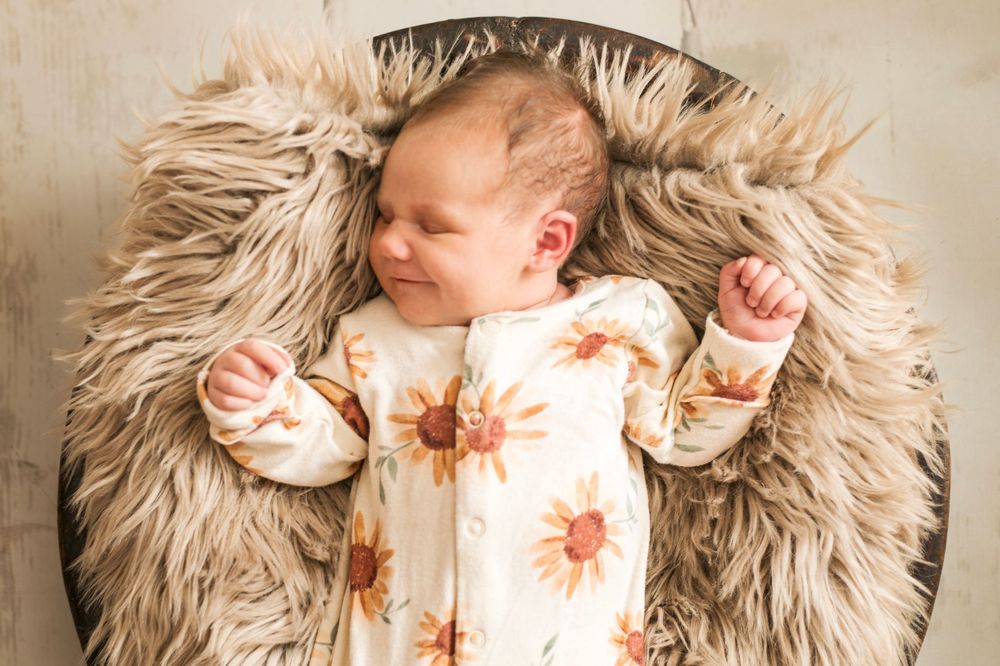 Newborn asleep, smiling, led in bowl.