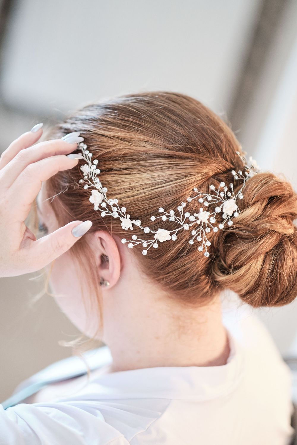Delicate pearl and crystal bridal hair accessory adorns an elegant updo hairstyle.