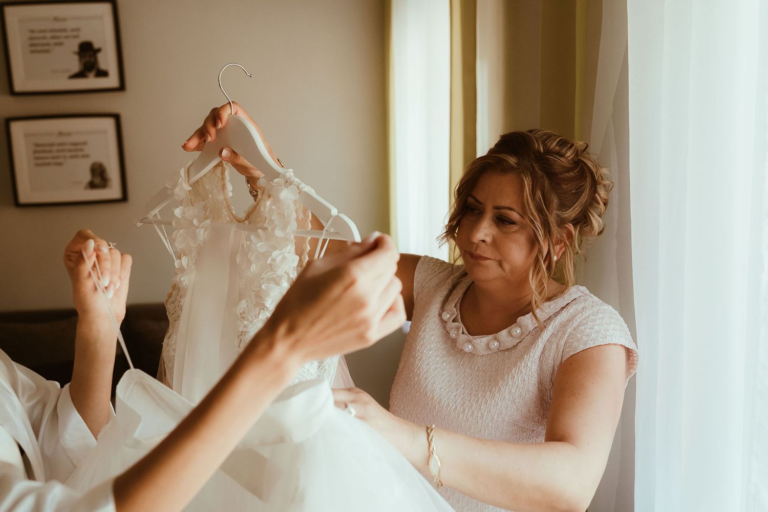 Wedding dress preparations with lace details being examined in natural light.