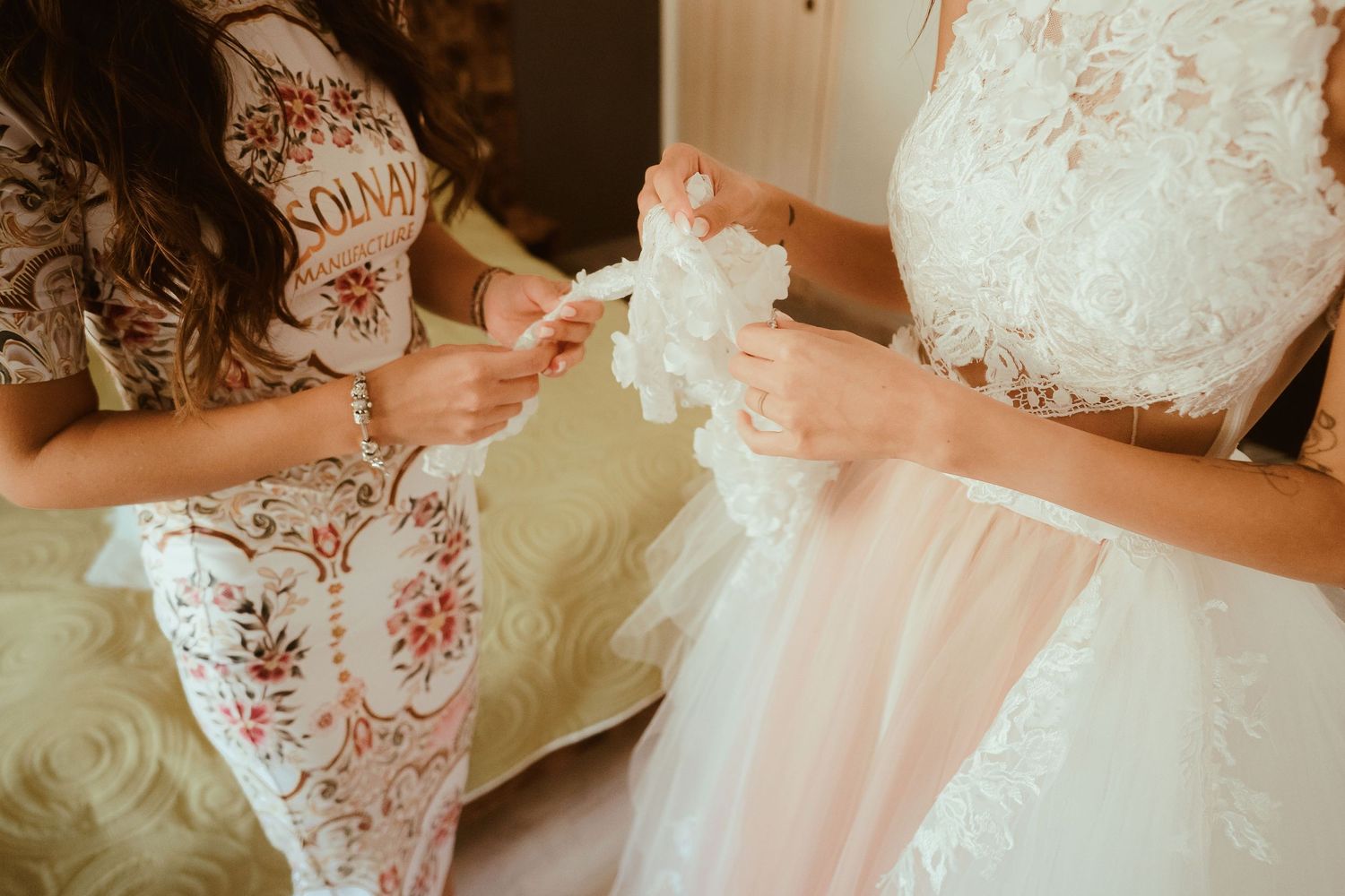 Detail shot of hands adjusting white tulle wedding dress fabric.