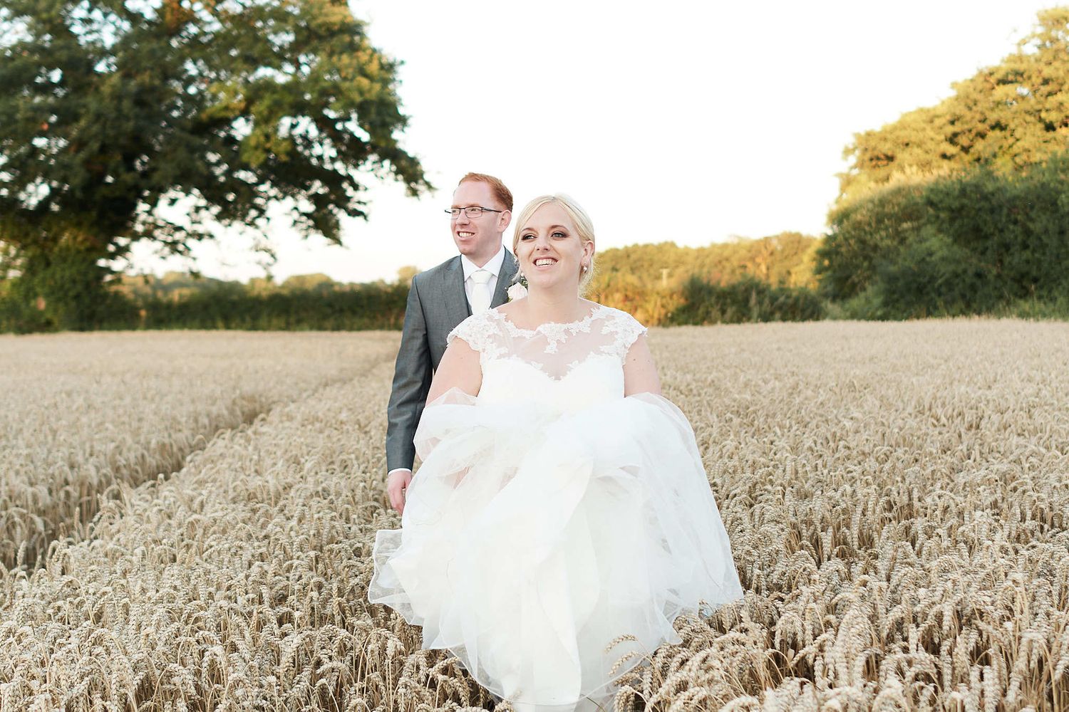bride and groom walk through a norfolk wheat field at sunset by faye amare photography