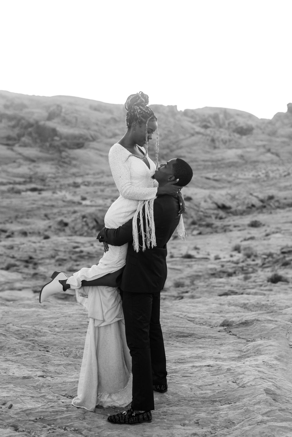 Black and white photo of romantic lift pose in desert setting.