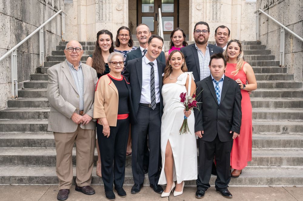 Wedding party gathered on stone courthouse steps for a formal group photo.