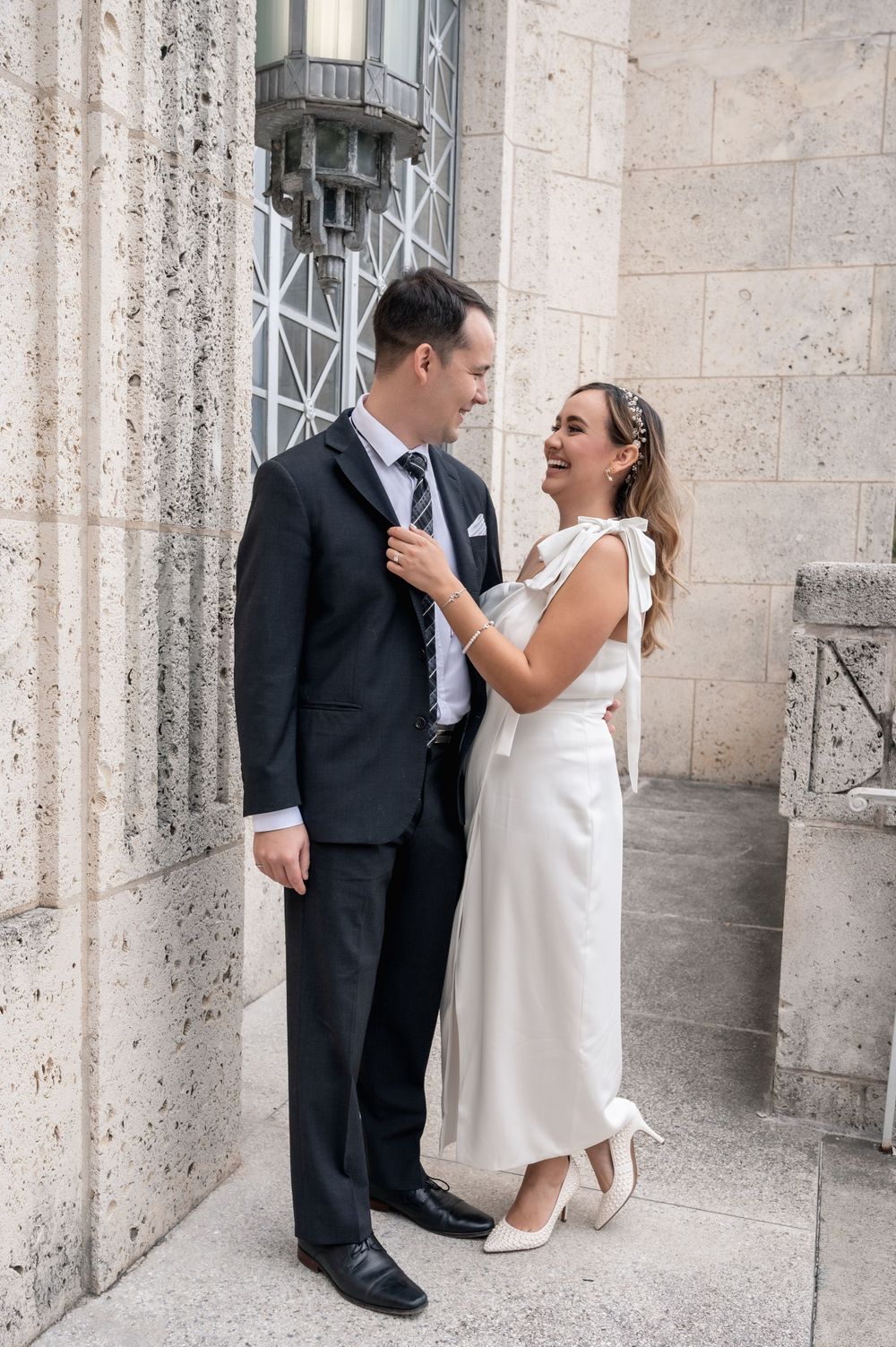 Intimate moment between newlyweds against textured stone courthouse wall.