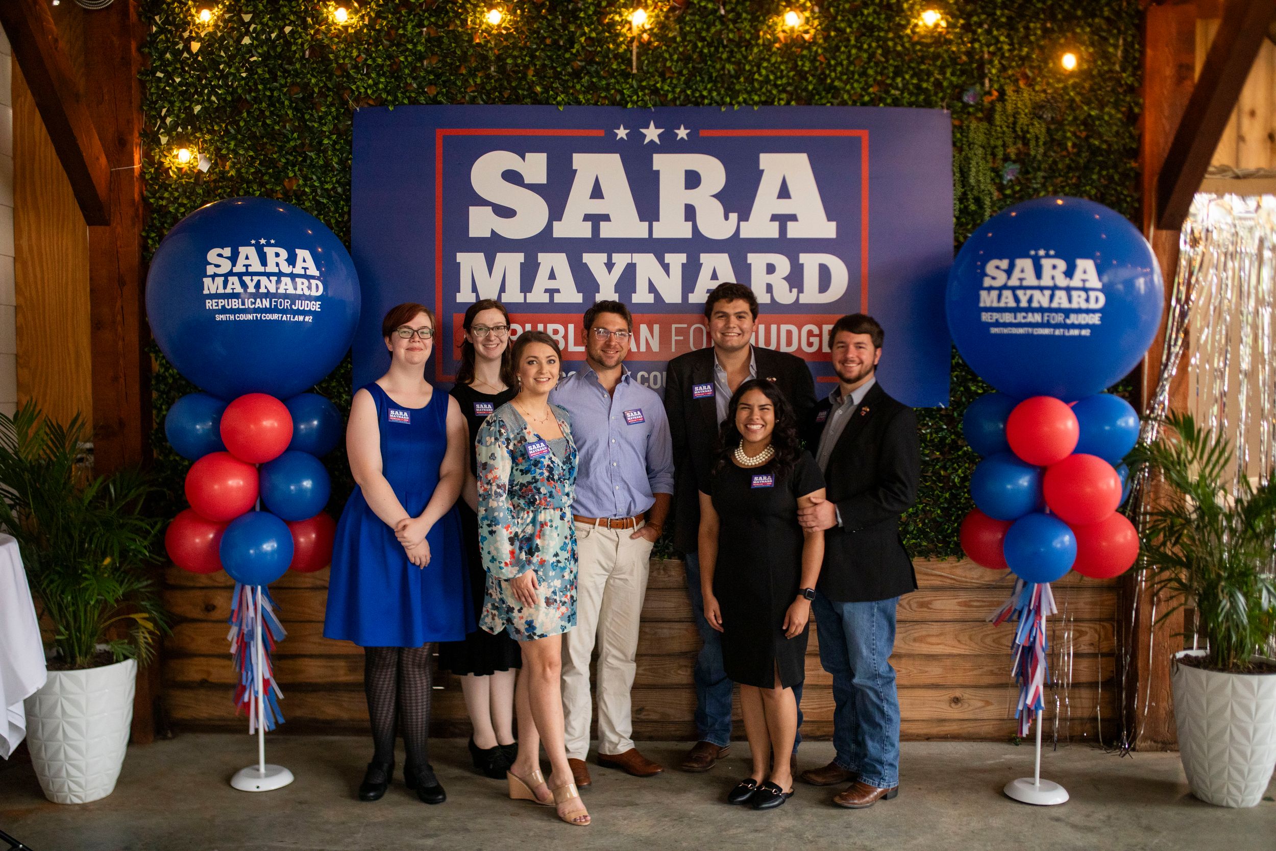 A political campaign event setup with blue and red balloons and campaign signage.