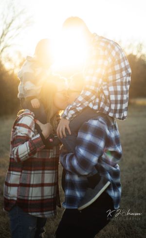 Golden sunlight illuminates two people in plaid shirts standing close together outdoors.
