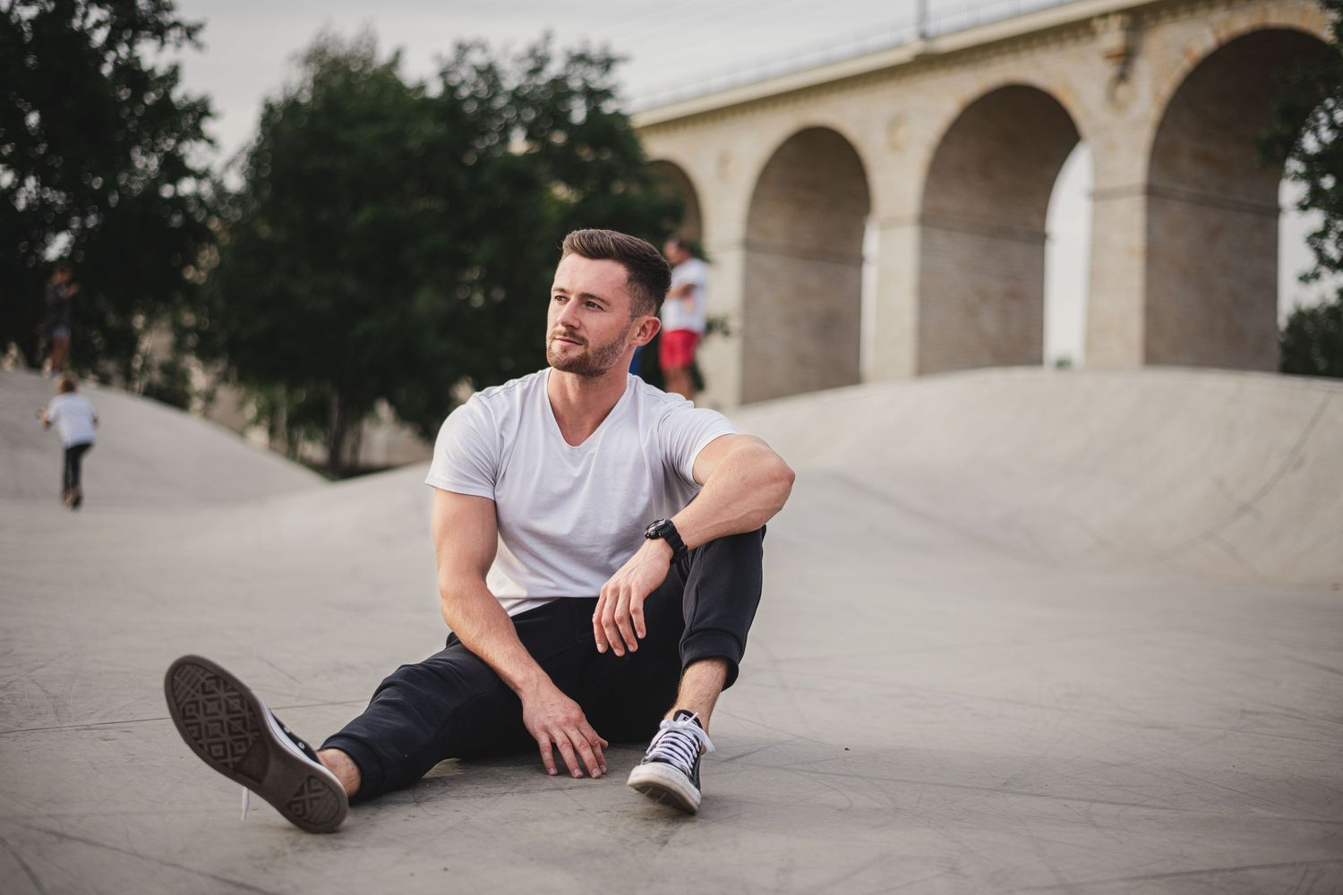 A casual portrait taken near an arched bridge structure.