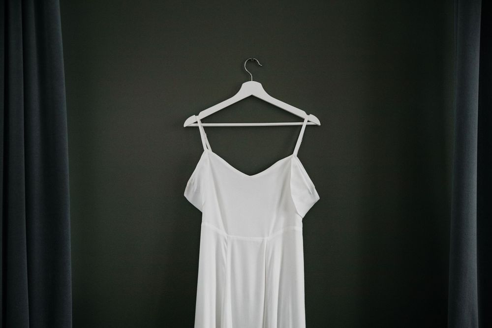 White wedding dress on a hanger against a dark background.