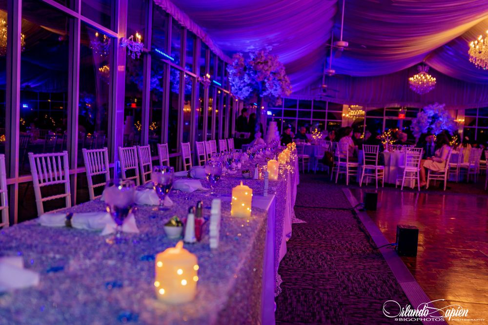 Wedding reception hall decorated with dramatic purple and blue lighting effects and elegant table settings.