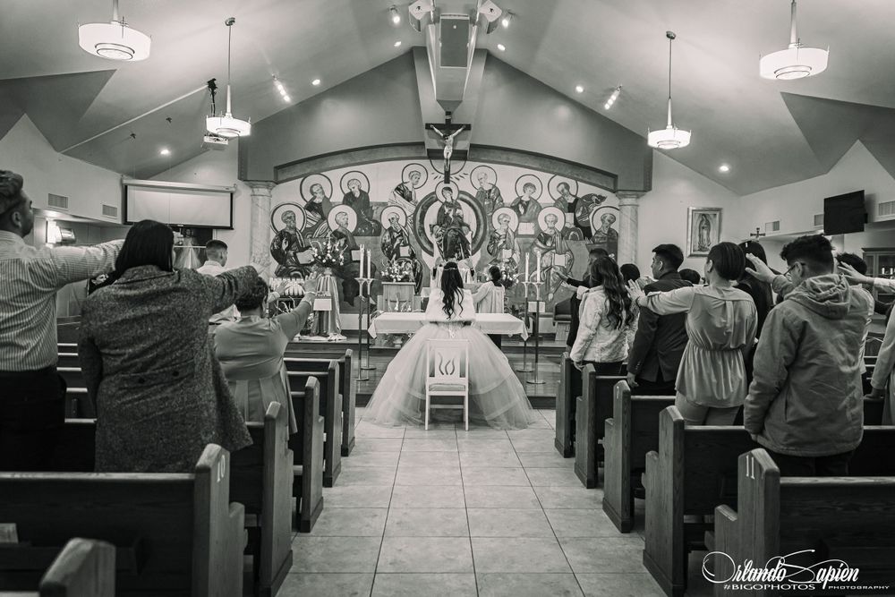 Wide angle view of a church interior with rows of pews and decorative lighting.