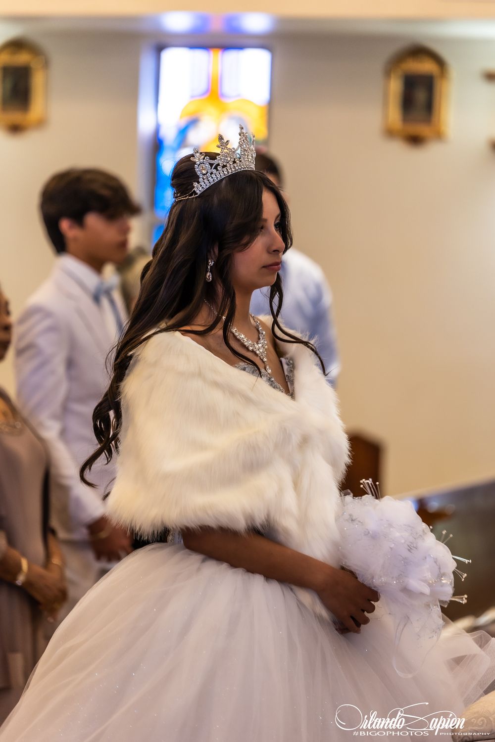 A person in a white ball gown and tiara during a celebration.