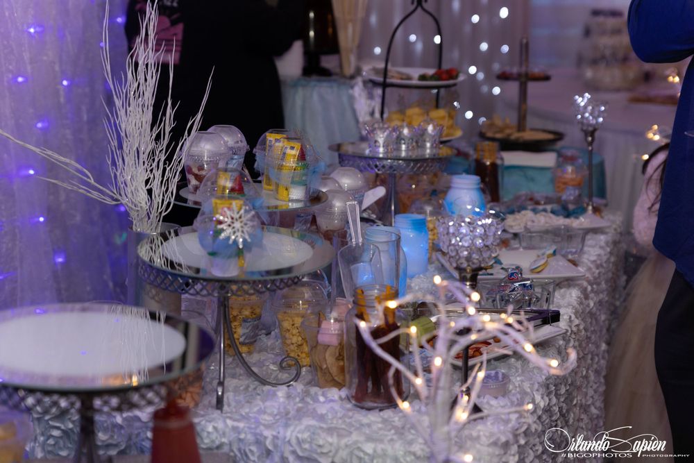 Elegant wedding reception decor with crystal chandeliers and white floral arrangements in a draped tent venue.