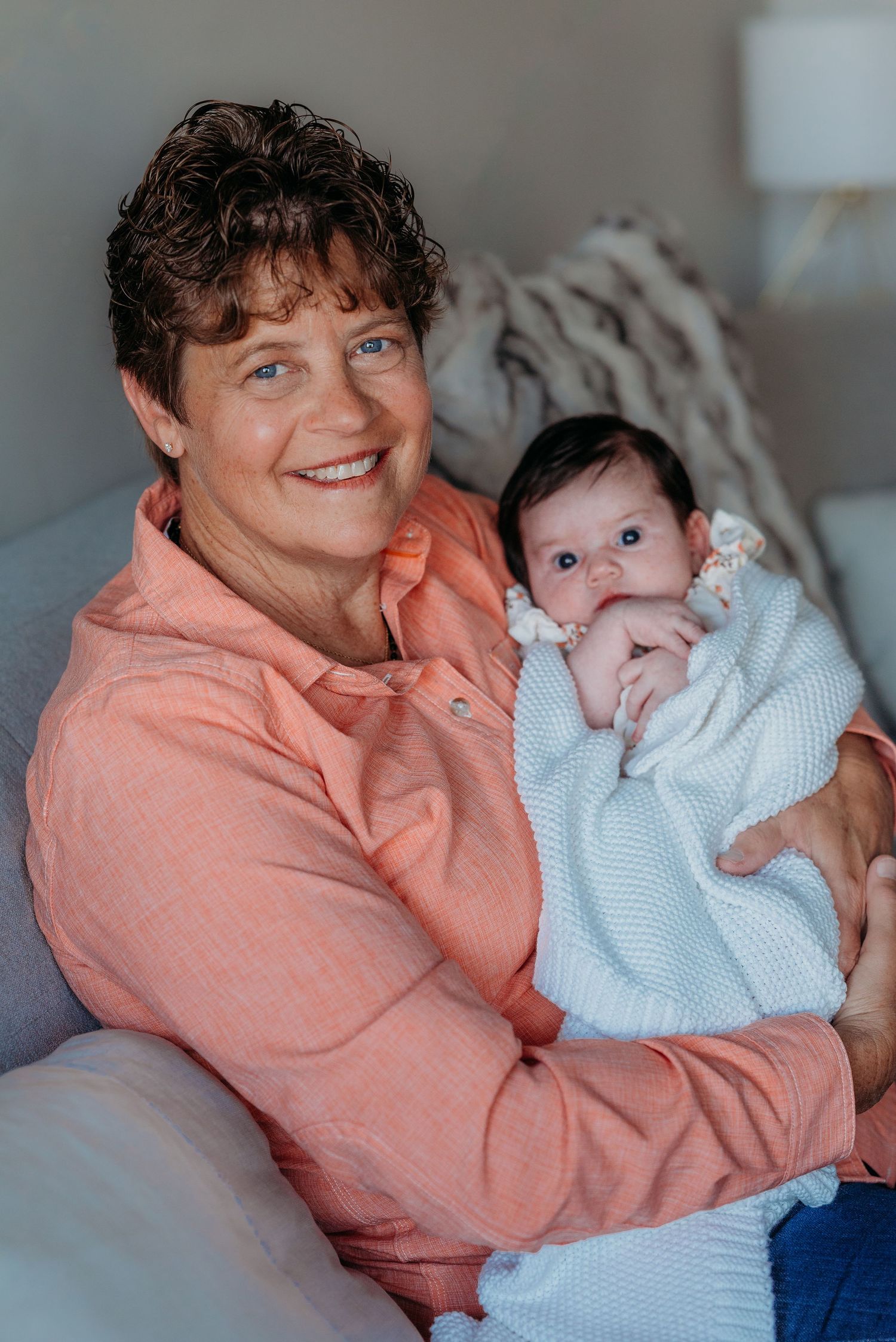 grandma holding a baby wrapped in white blanket
