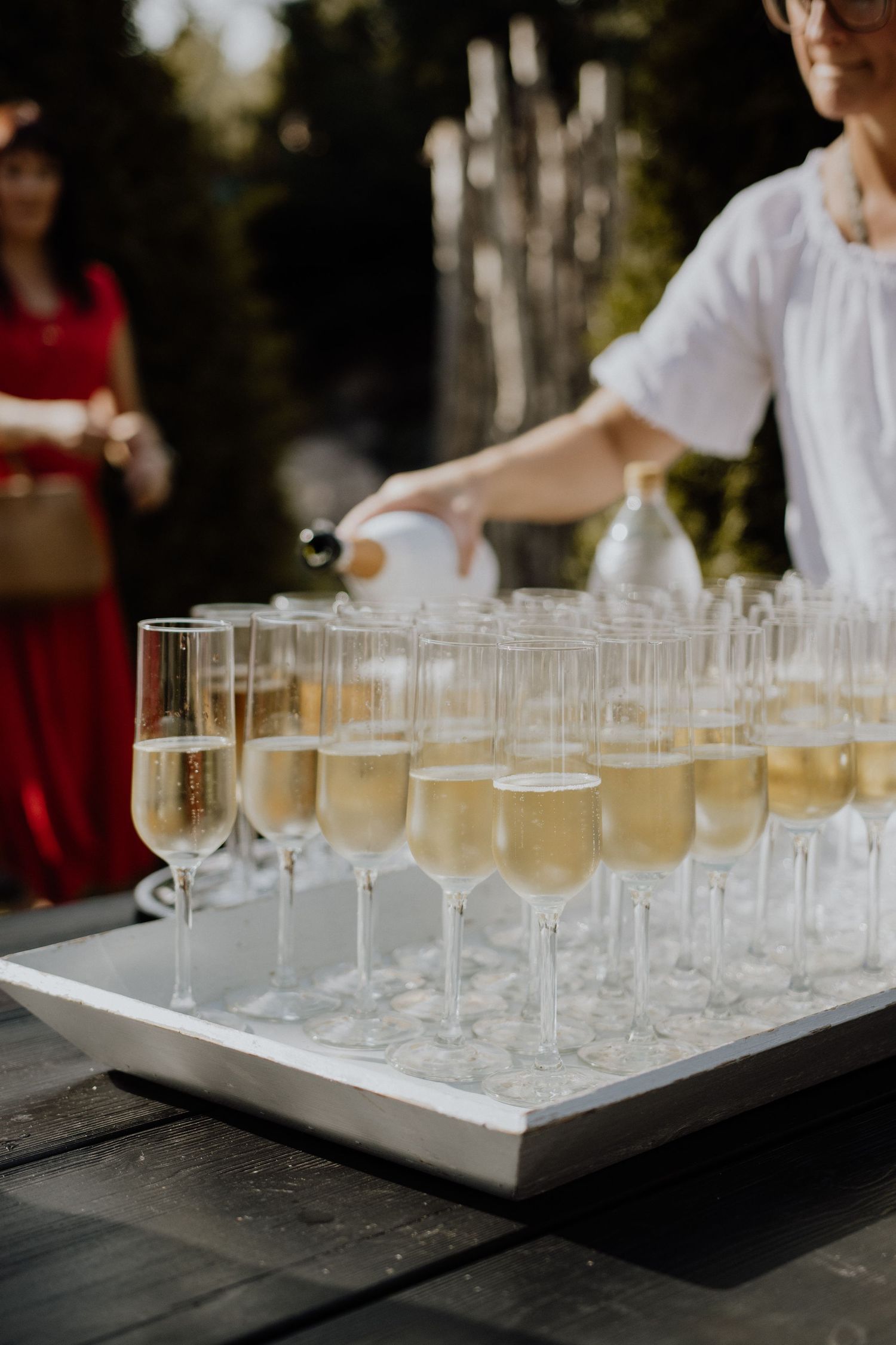 Champagne flutes filled with sparkling wine being arranged on a white serving tray at an elegant event.