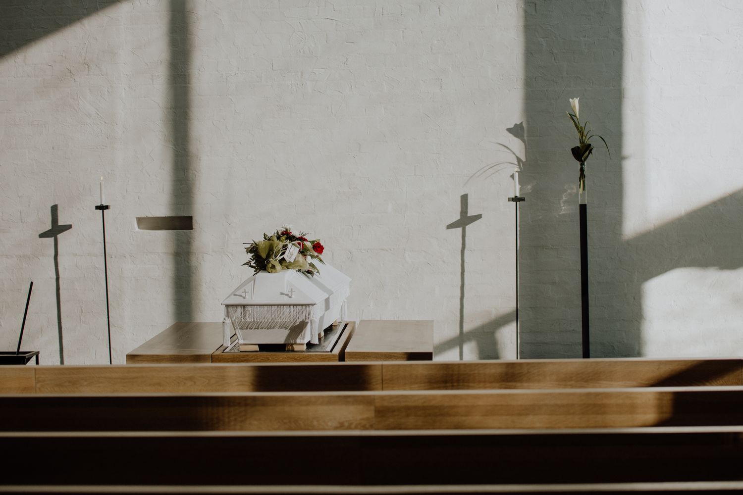 Simple church altar with wooden crosses and floral arrangement in natural light.