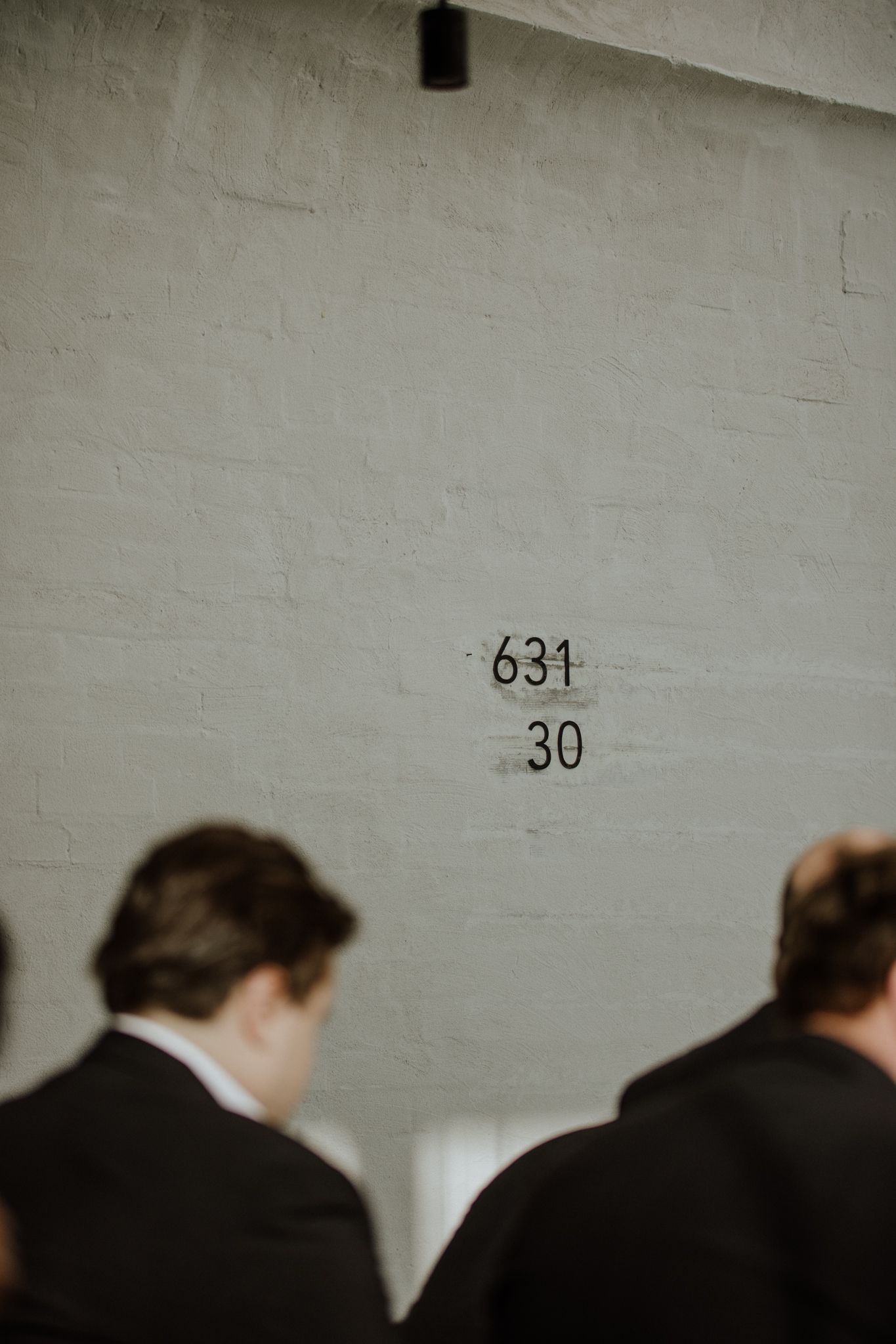 Dark silhouettes against white wall with numbers 631 30 written on it.