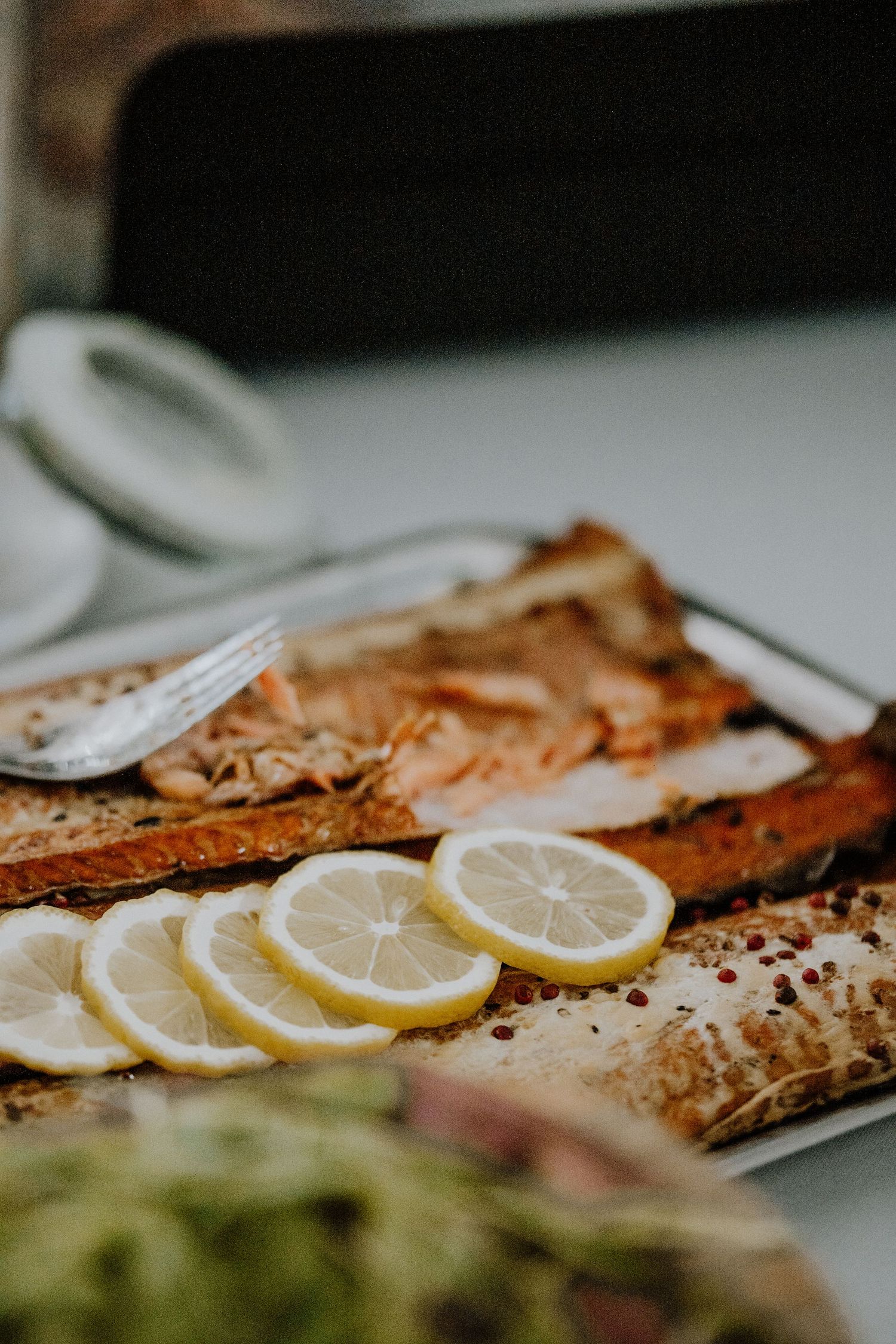 Grilled salmon fillet garnished with fresh lemon slices on a white plate.
