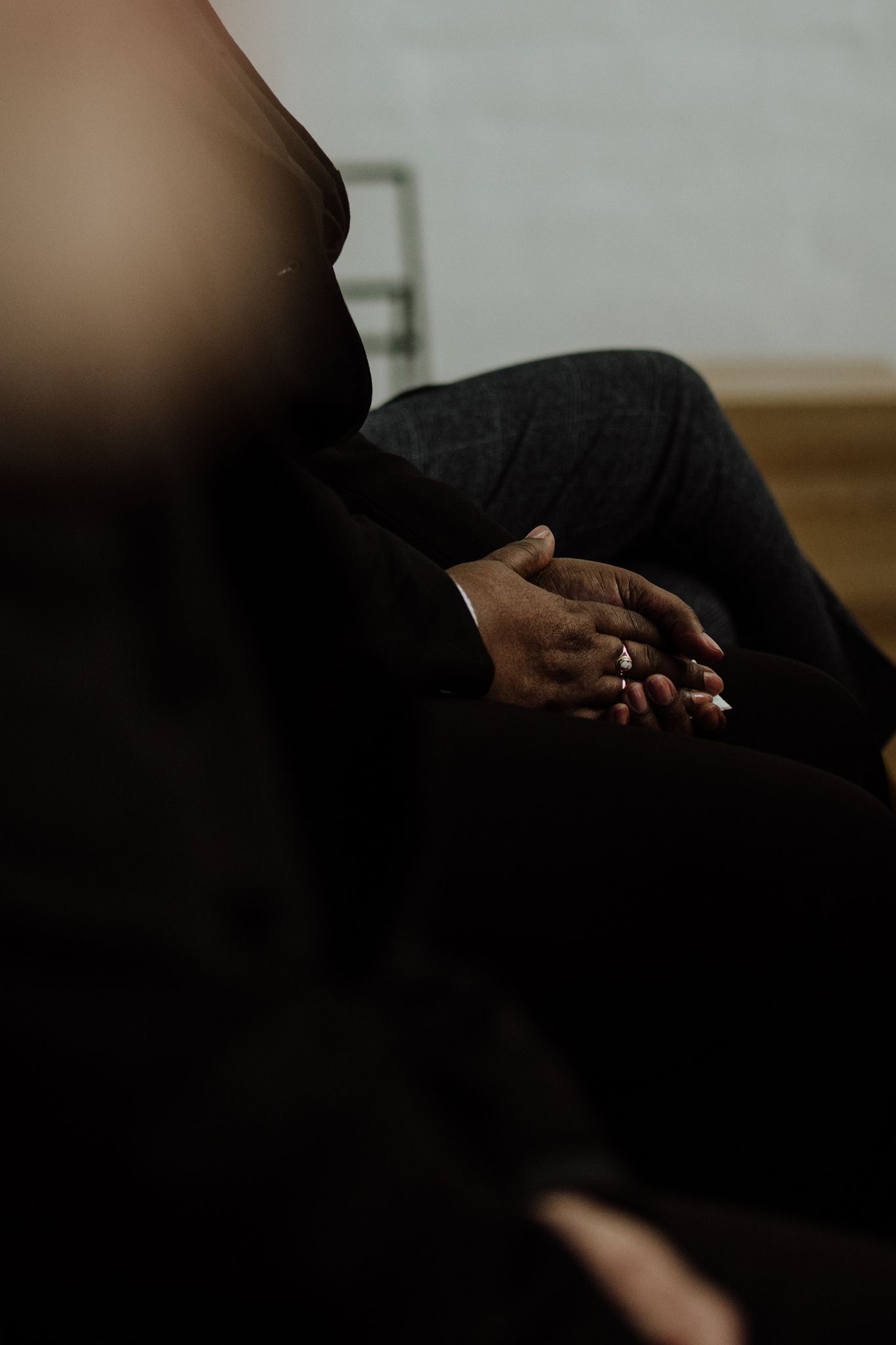 Close-up of hands with wedding ring clasped in prayer or contemplation.