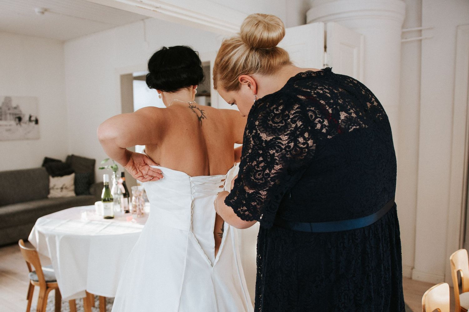 Behind-the-scenes moment of wedding dress preparation in an indoor setting.