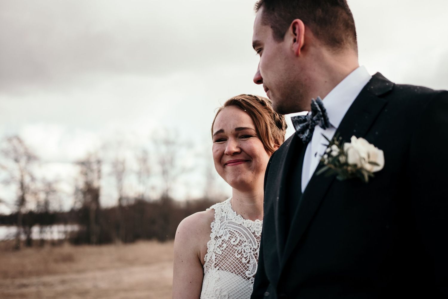 Intimate wedding moment captured outdoors with a natural winter landscape backdrop.