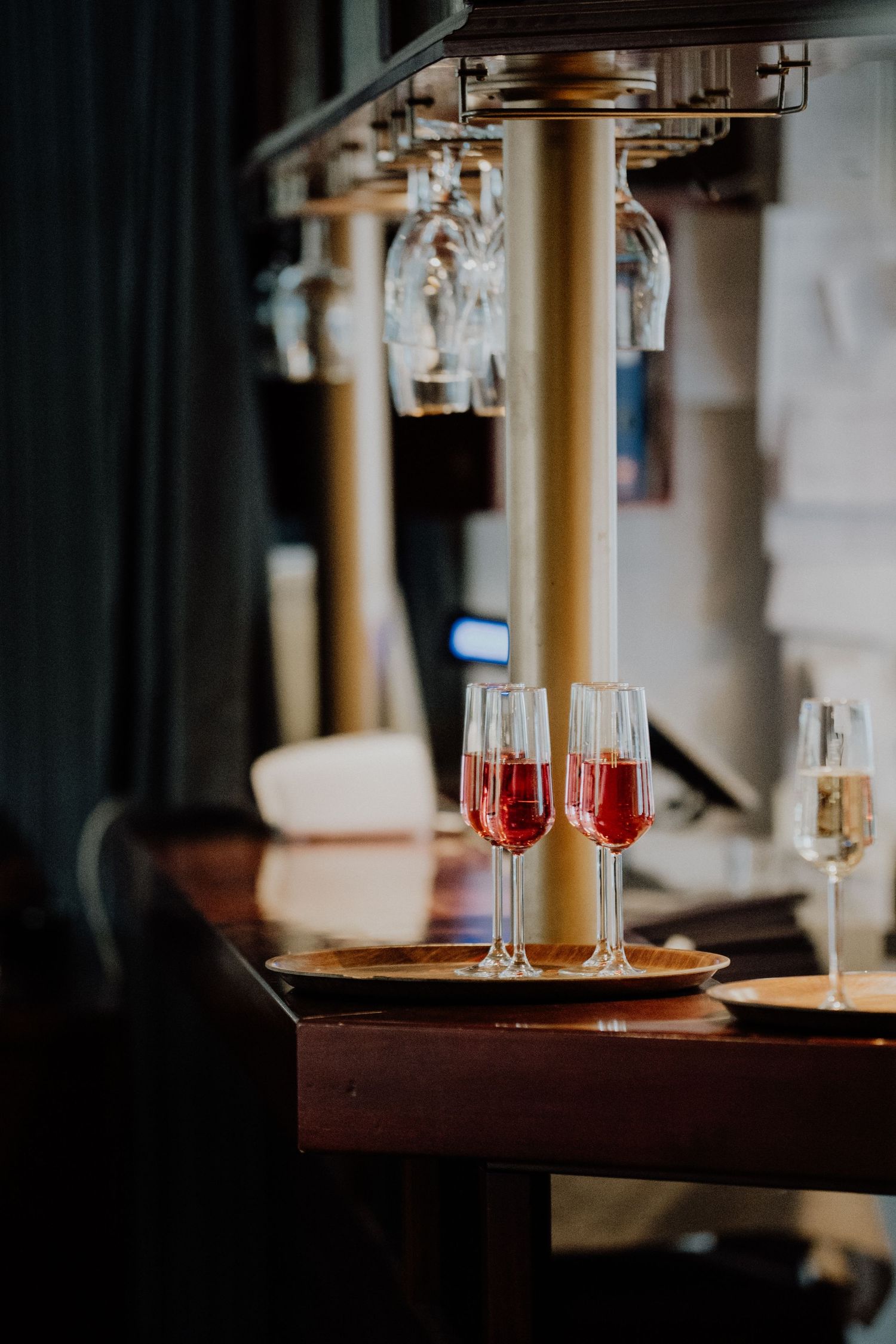 Elegant wine glasses filled with red and white wine displayed on a dark wooden bar counter.